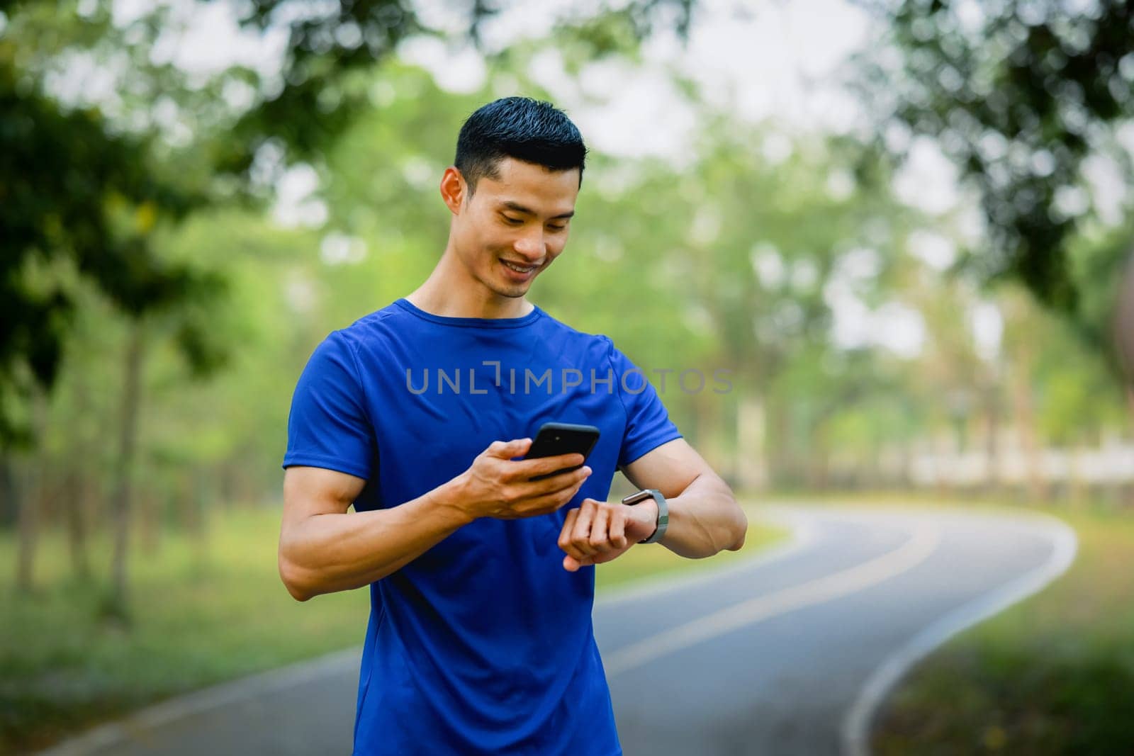 Satisfied male athlete checking training program on smartphone application. Technology health, wellness concept by prathanchorruangsak