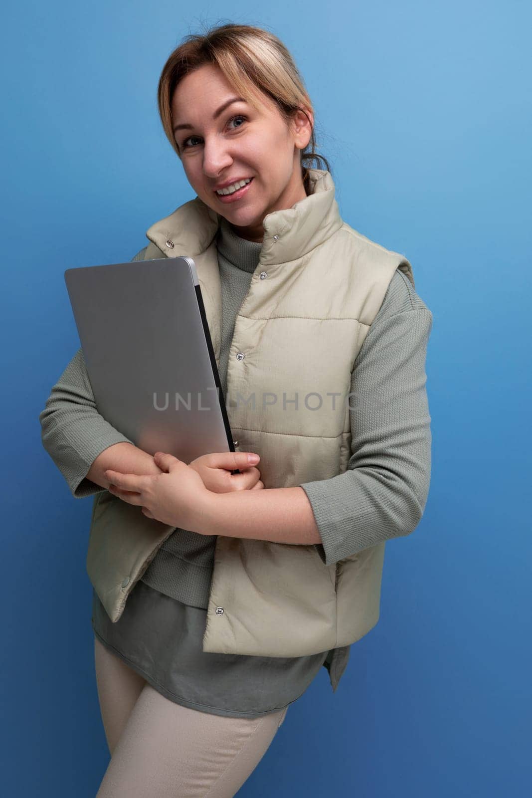 young blondie business woman with a laptop in her hands on a blue background.