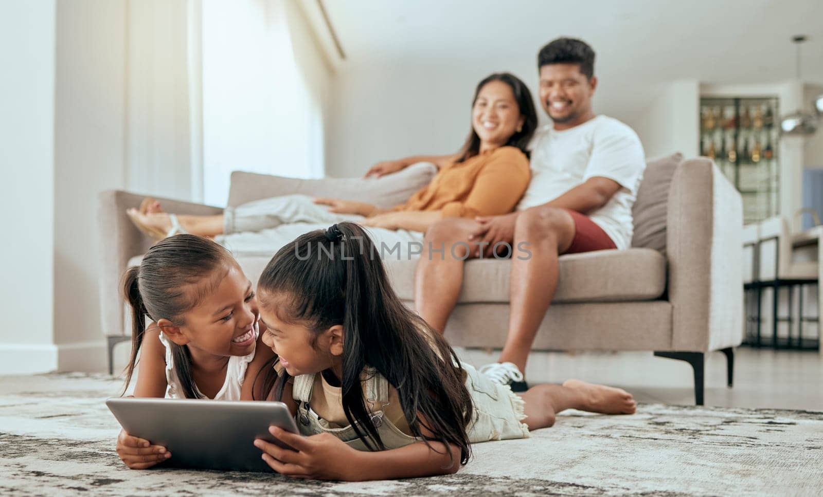 Laughing children, tablet or relax parents on sofa in house living room in fun esports gaming, education video or movie streaming app. Smile, comic and happy kids bonding in family home on technology by YuriArcurs