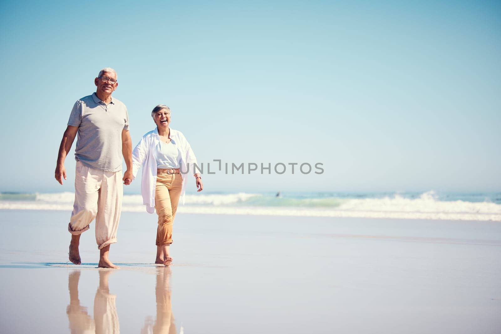 Holding hands, summer and an old couple walking on the beach with a blue sky mockup background. Love, romance or mock up with a senior man and woman taking a walk on the sand by the ocean or sea by YuriArcurs