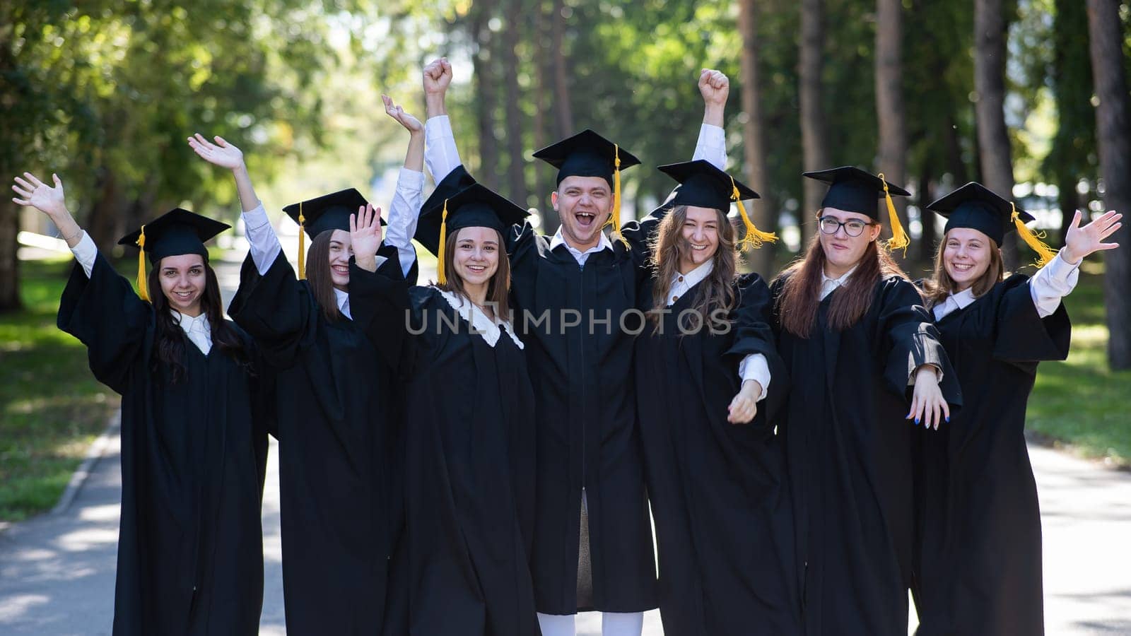 Group of happy graduates in robes outdoors