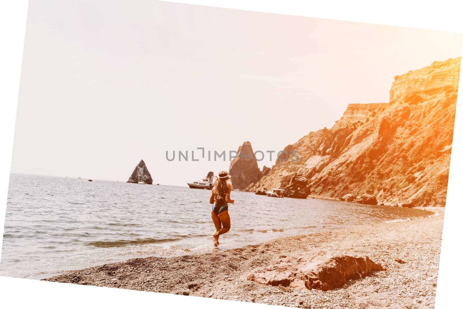 Woman travel summer sea. A happy tourist in a blue bikini enjoying the scenic view of the sea and volcanic mountains while taking pictures to capture the memories of her travel adventure