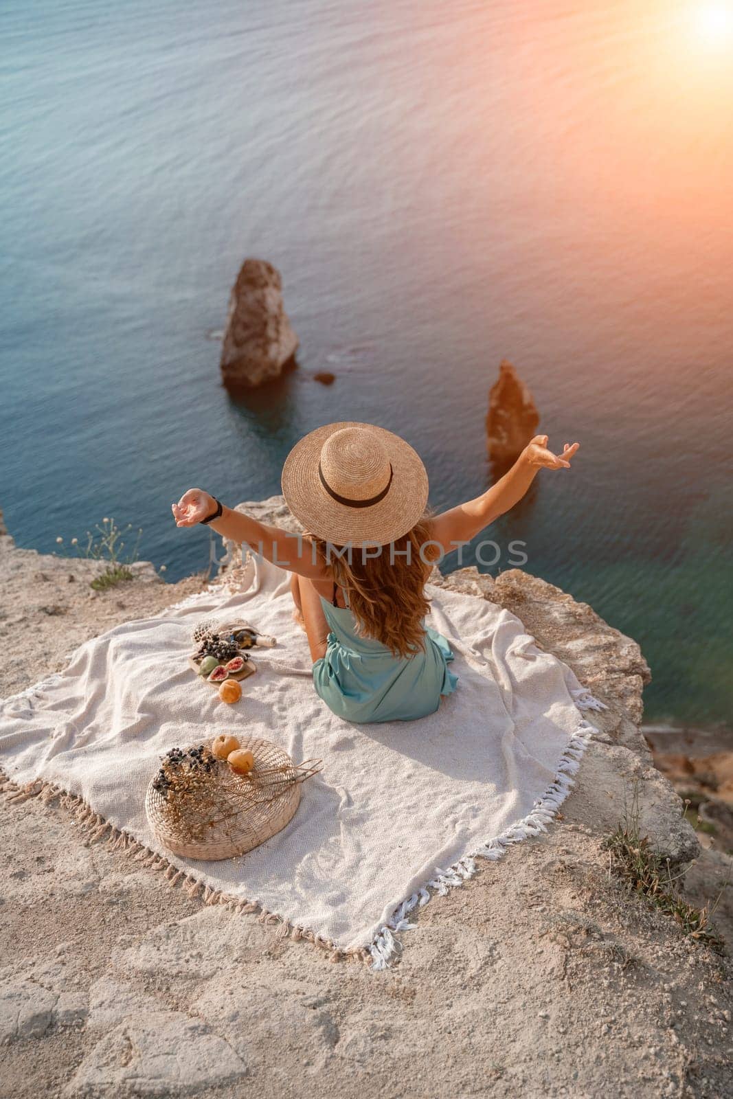 woman sea travel. photo of a beautiful woman with long blond hair in a pink shirt and denim shorts and a hat having a picnic on a hill overlooking the sea by Matiunina