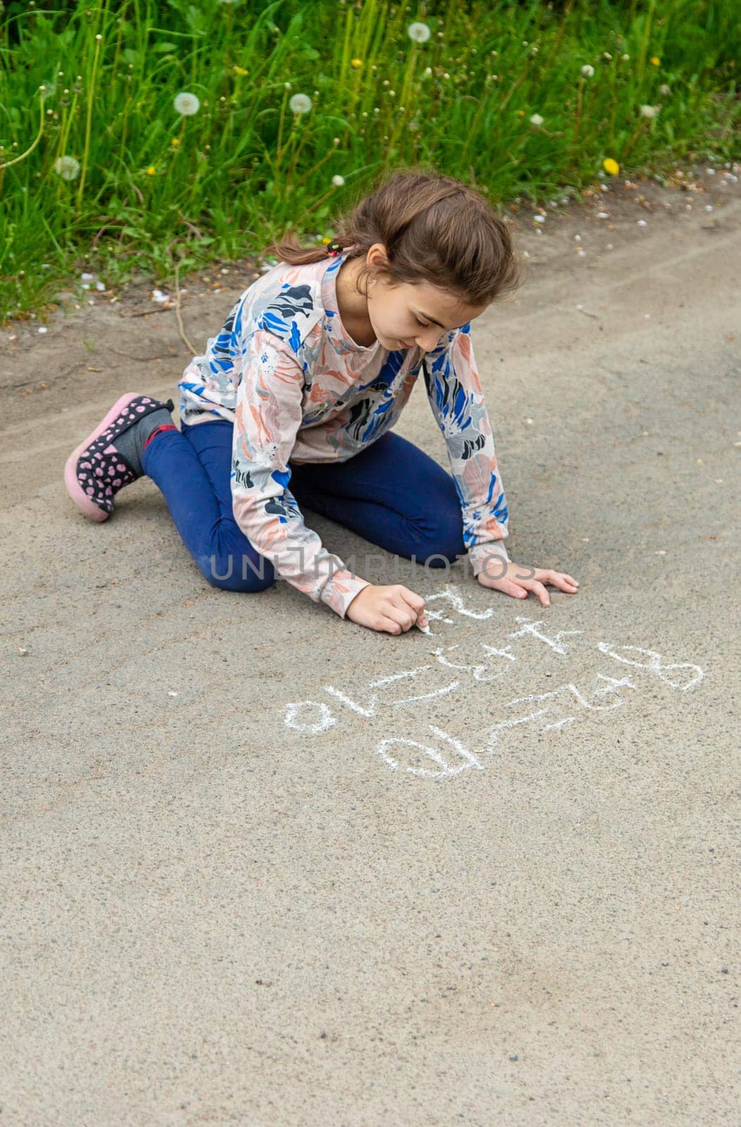 Children draw equations on the pavement with chalk. Selective focus. by yanadjana