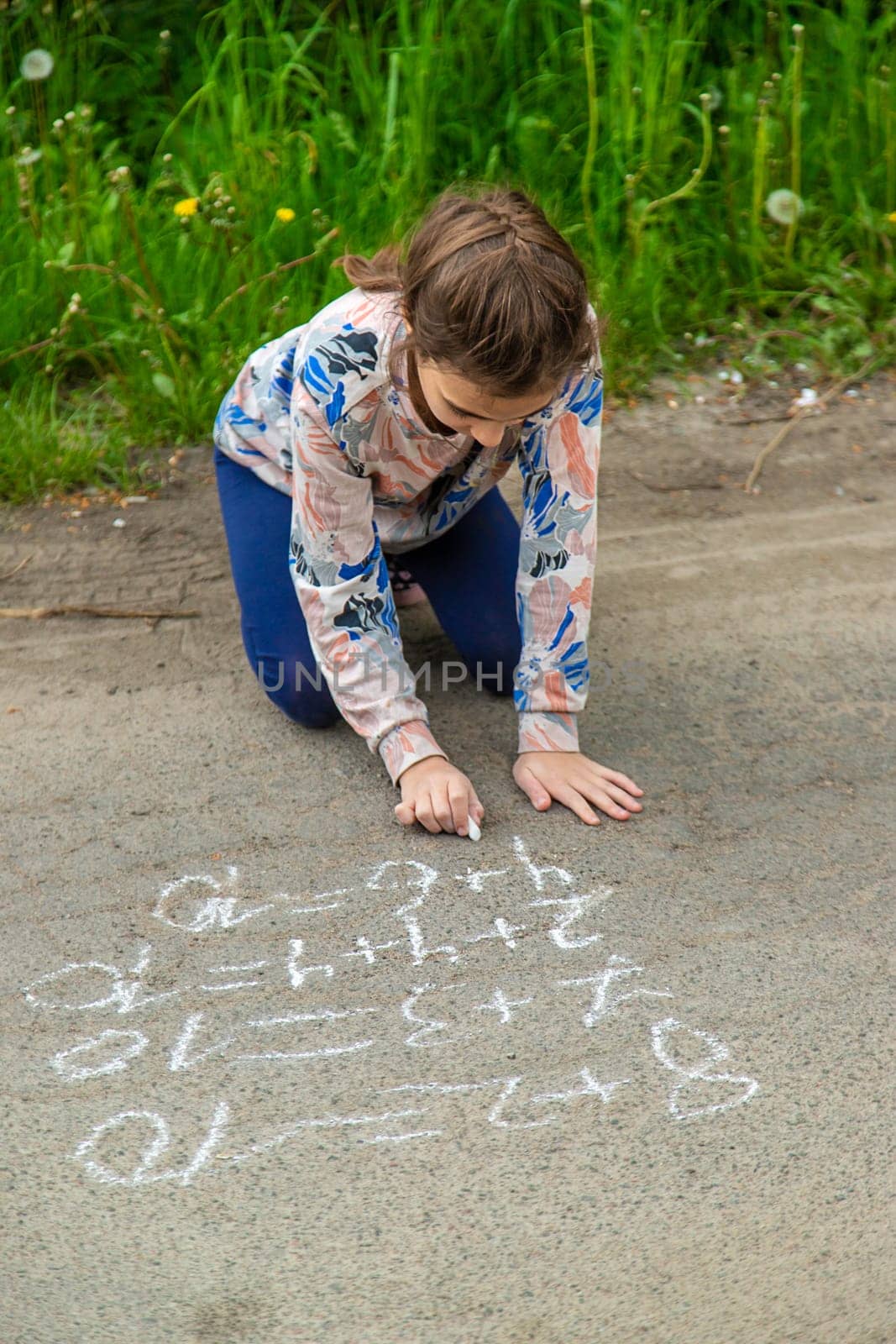 Children draw equations on the pavement with chalk. Selective focus. Kid.