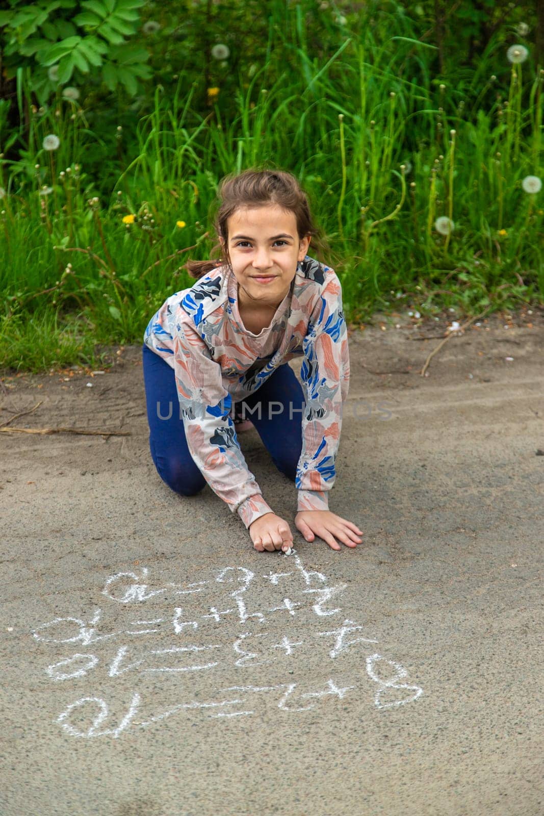 Children draw equations on the pavement with chalk. Selective focus. Kid.