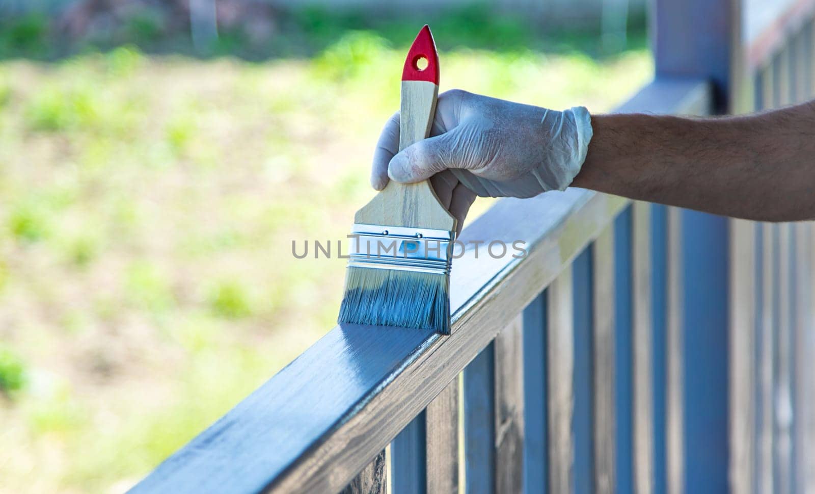 Painting a wooden board with a gray brush. Selective focus. Nature.