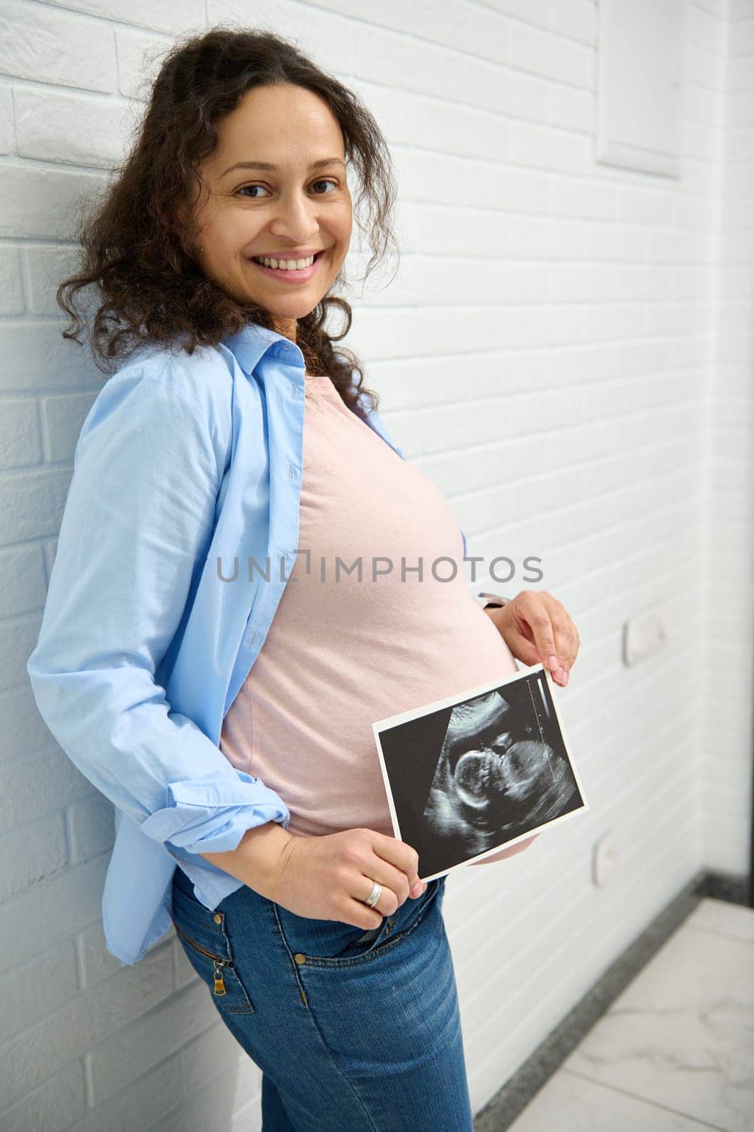 Happy pregnant woman holding ultrasound scan of her baby. Pregnancy. Obstetrics and gynecology concept. Health care by artgf