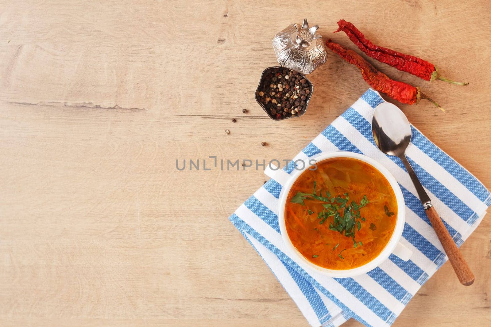 Vegetable soup with potatoes, cabbage, carrots and onions in a white bowl on the kitchen table. Vegetarian food. Copy space