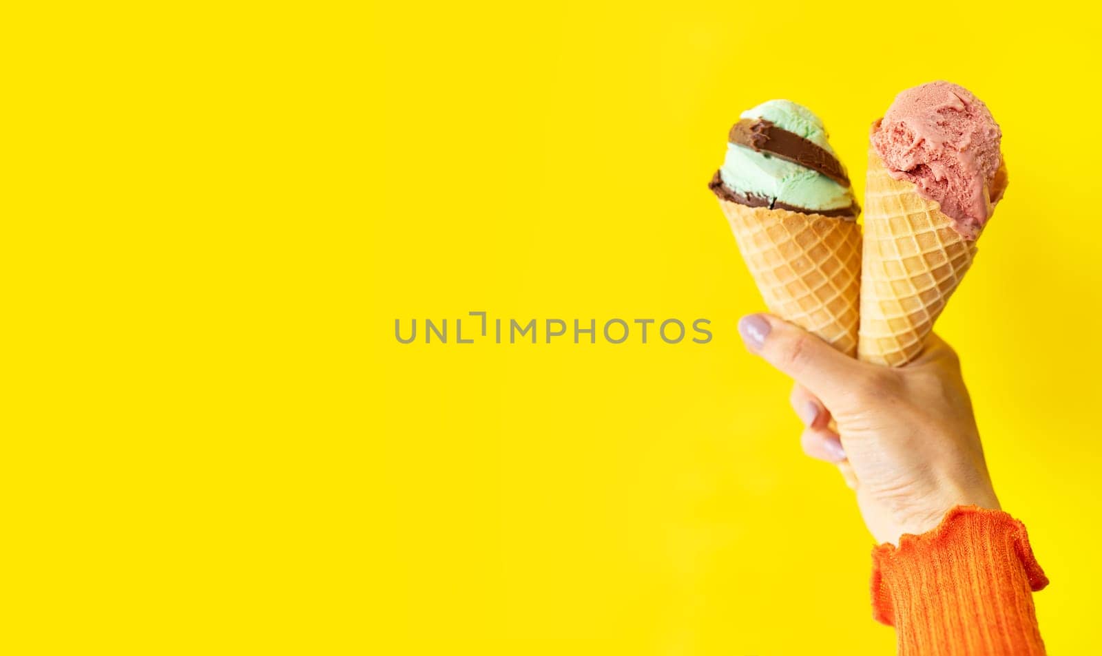 A cone of bright, tasty, refreshing ice cream on a yellow bright background. A woman holds ice cream in her hands, a place for an inscription. The concept of vacation, vacation at sea. by sfinks