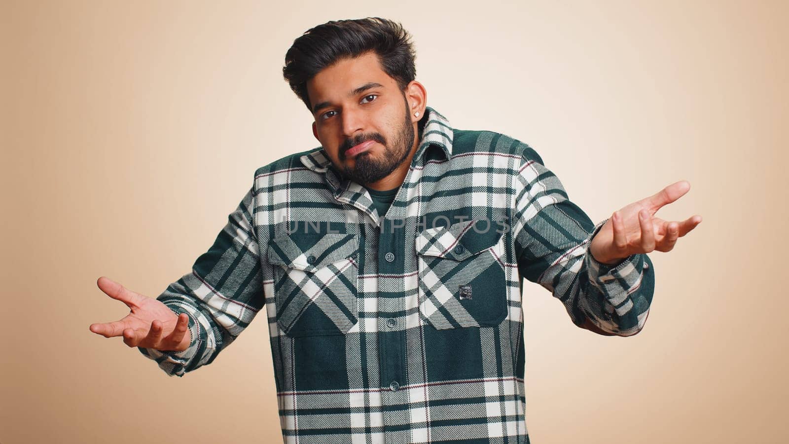 No idea, I dont know answer. Puzzled clueless uncertain indian handsome man raising hands in helpless gesture, embarrassed confused by difficult question. Confused one guy on beige studio background