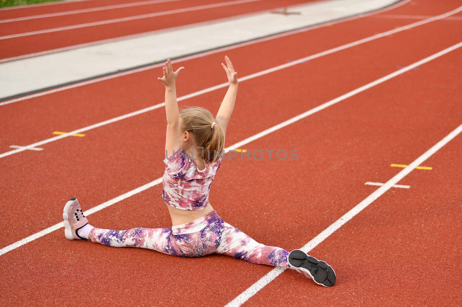 A girl in a legging doing splits at the stadium by Godi