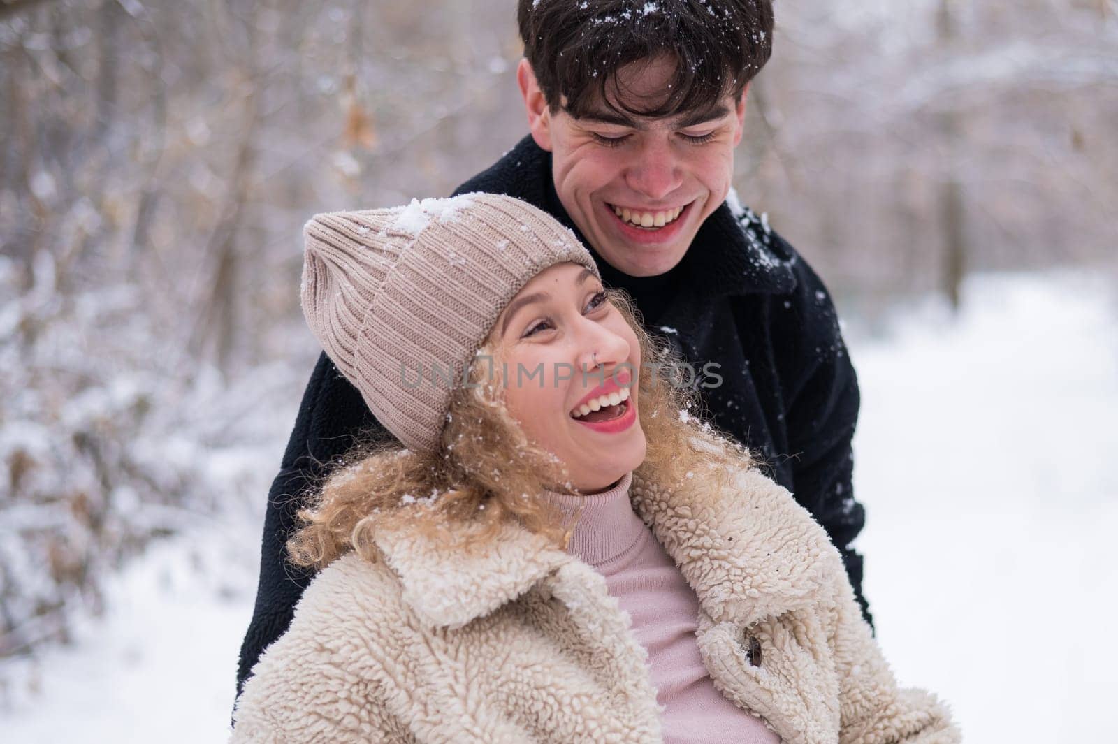 A young couple walks in the park in winter. Guy and girl hugging outdoors