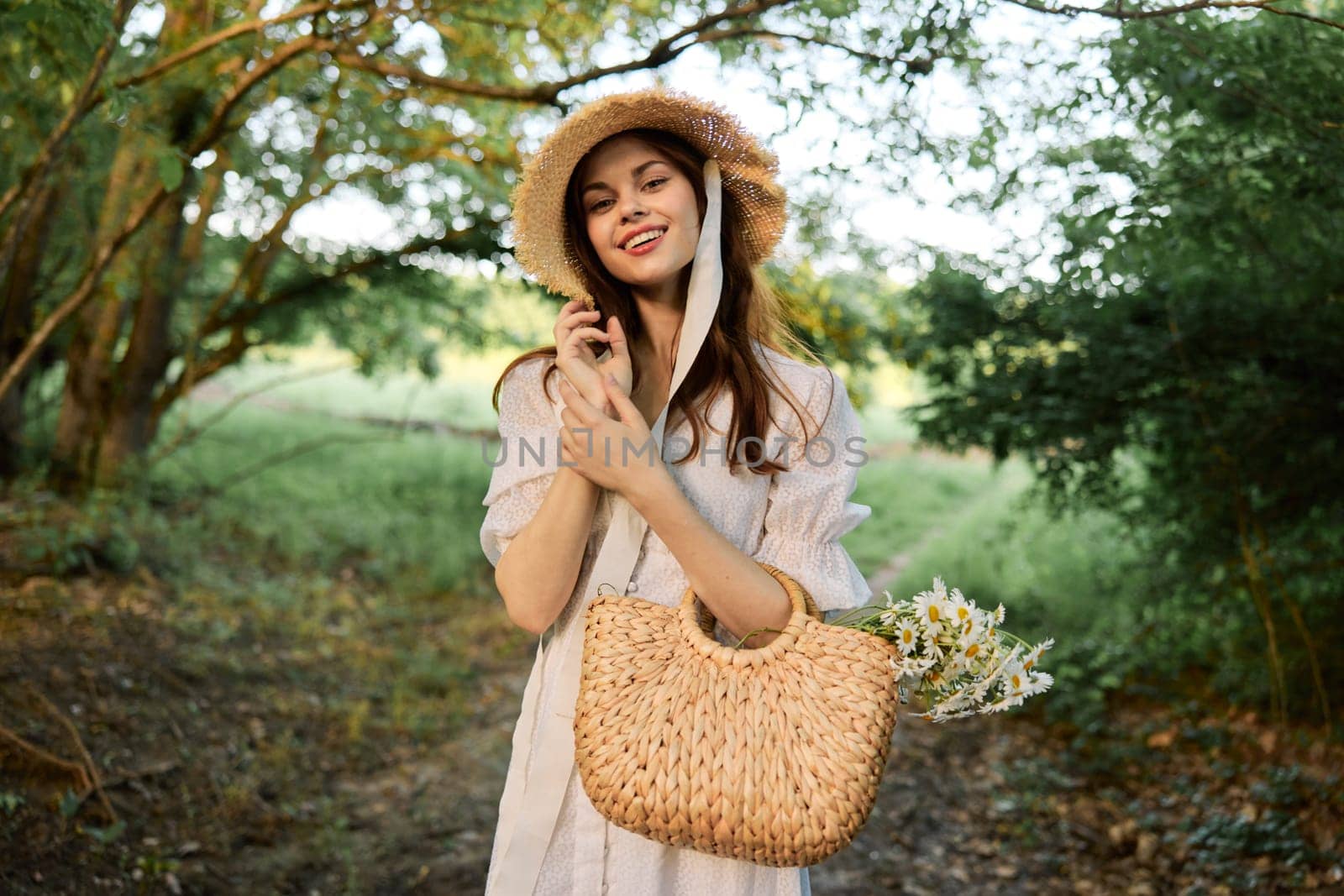 happy, smiling woman in a wicker hat with a basket of daisies in her hands walks through the forest. High quality photo
