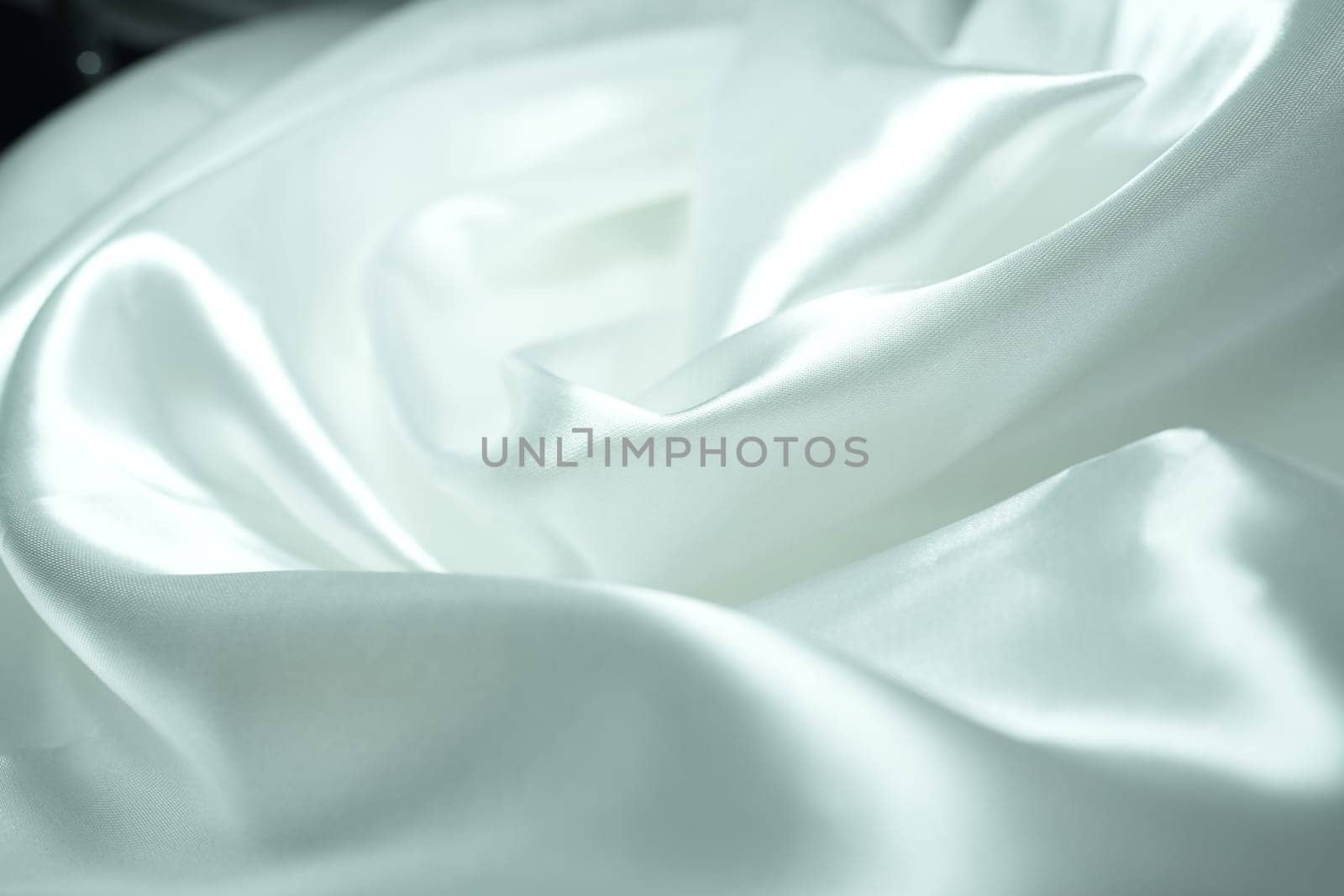 White satin fabric background with wavy soft folds for selling product. White Texture - light Wavy Glossy Silk Drapery. Shiny smooth fabric. Elegant background for design.