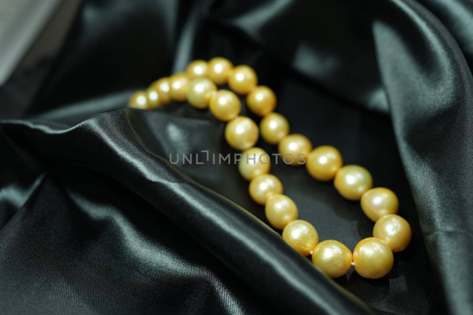 Golden Pearl necklace on black satin background by nantachai