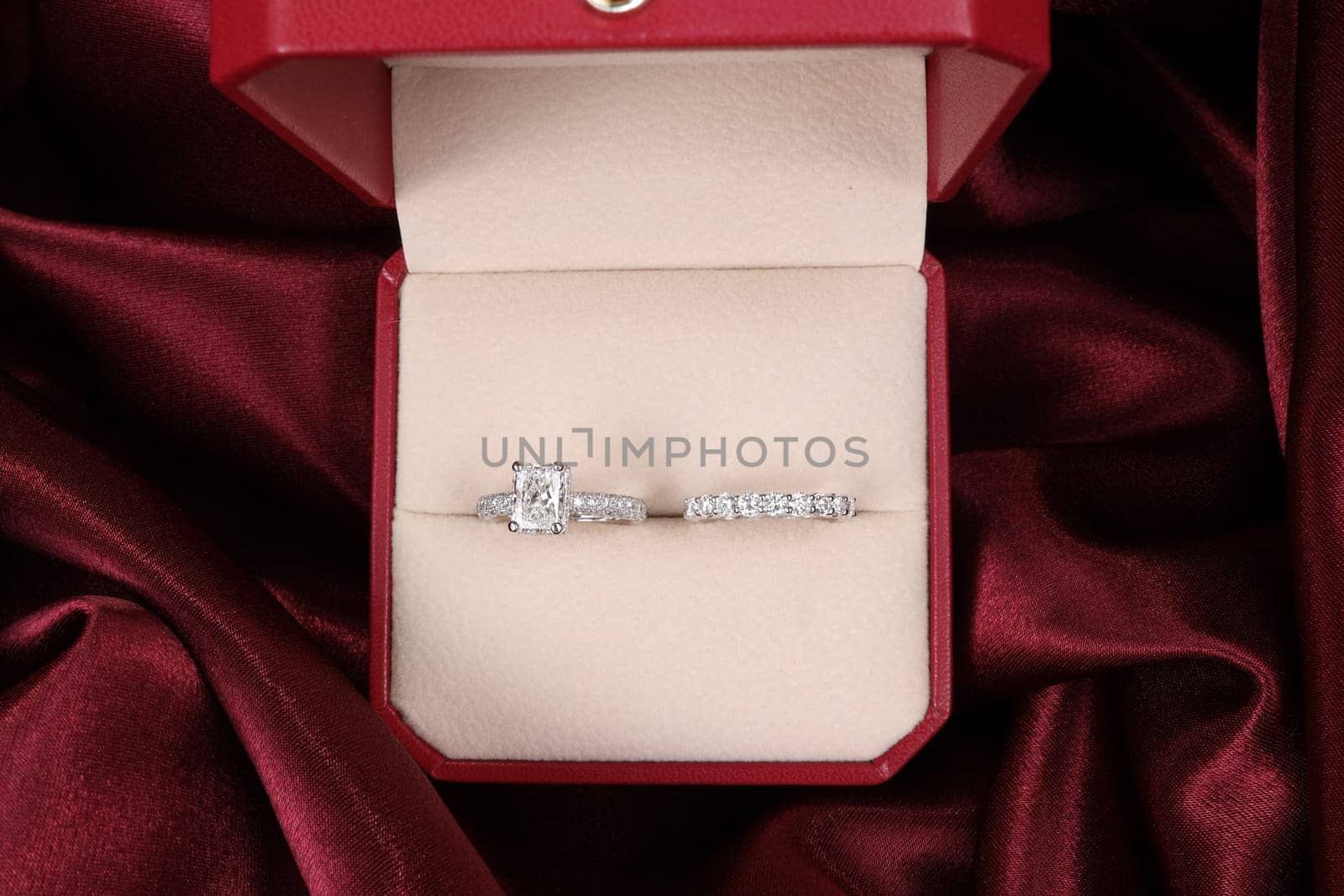 Luxury jewelryFine jewelry as diamond ring on white gold or platinum setting with red satin fabric background. Jewelry Luxury shop concept for engagement couple lover