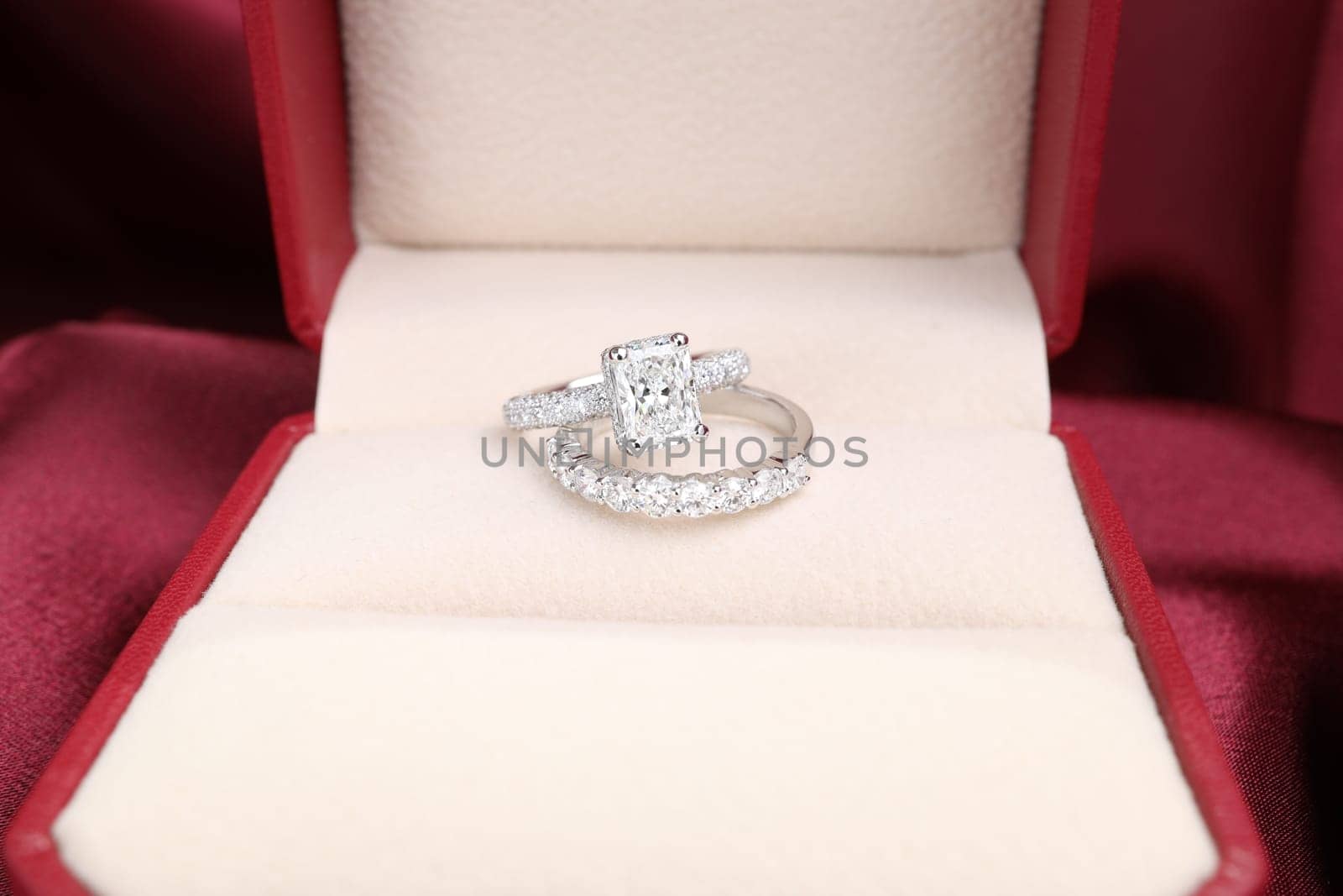 Luxury jewelryFine jewelry as diamond ring on white gold or platinum setting with red satin fabric background. Jewelry Luxury shop concept for engagement couple lover