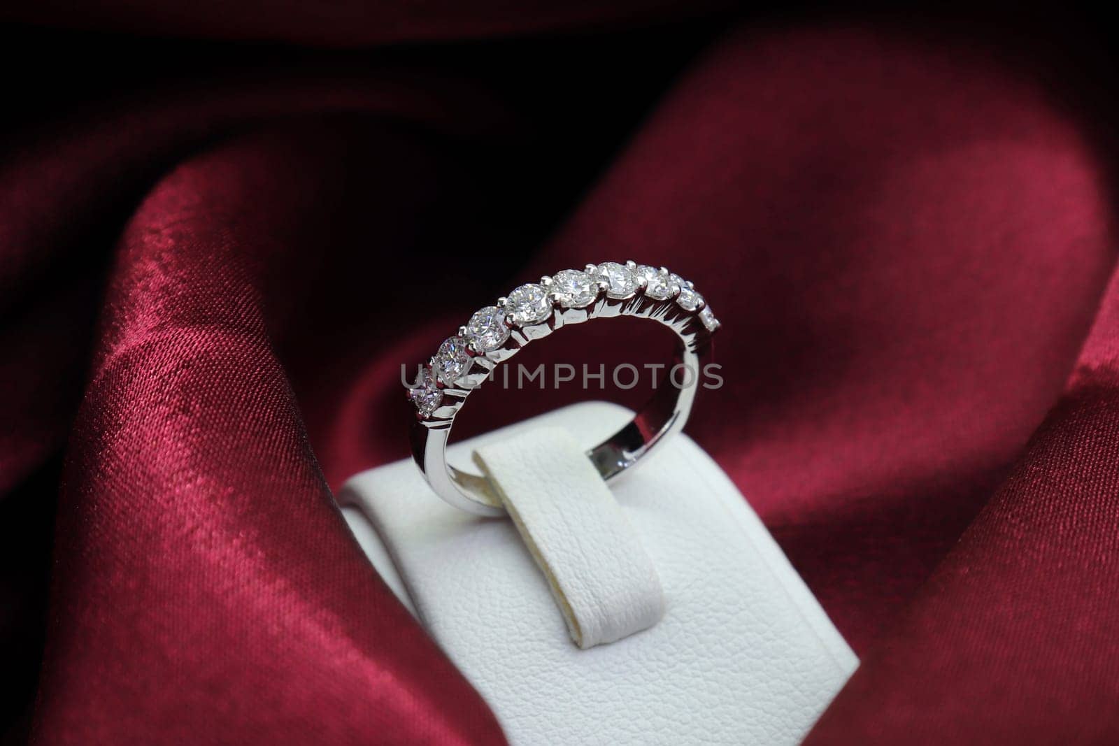 Luxury jewelryFine jewelry as diamond ring on white gold or platinum setting with red satin fabric background. Jewelry Luxury shop concept for engagement couple lover