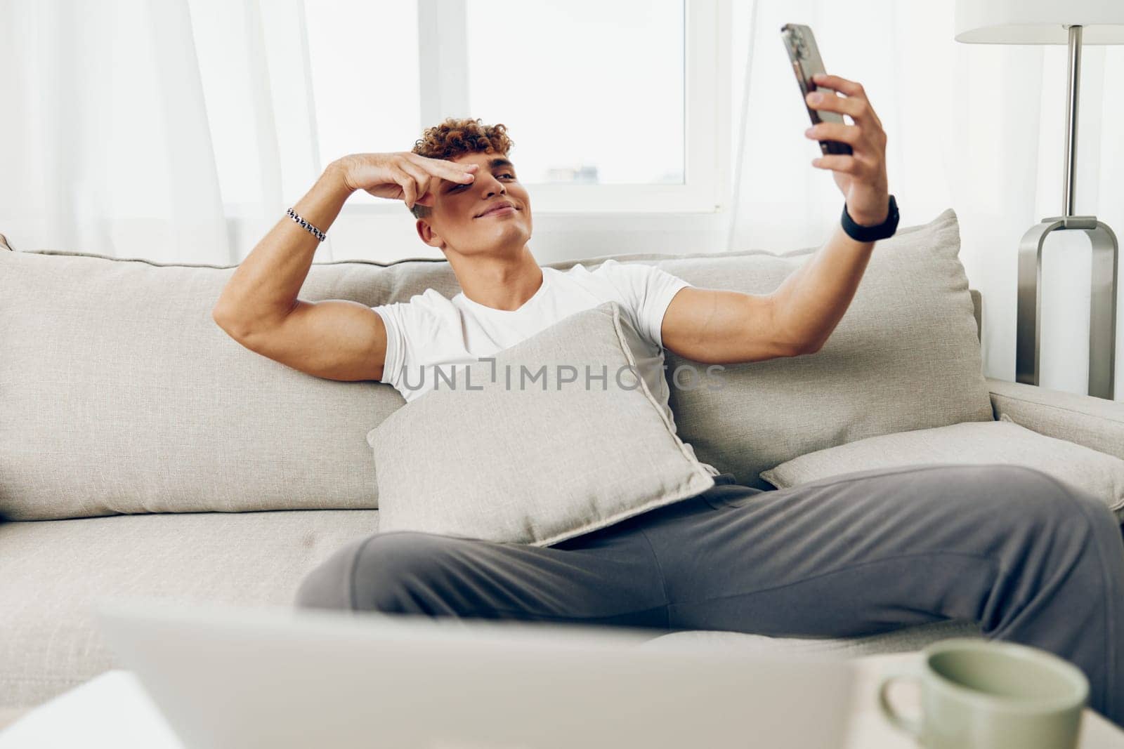 man interior sitting smile text couch smart student adult business holding internet young technology message mobile cellphone text message communication selfies modern