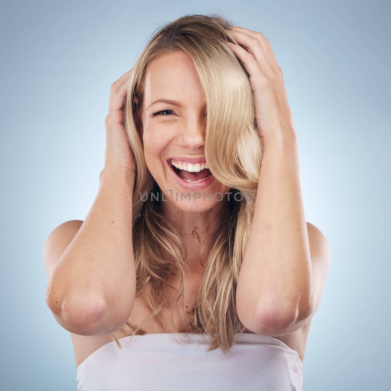 Face portrait, hair care and beauty of woman in studio isolated on a gray background. Keratin, cosmetics and laughing female model with blonde hairstyle after salon treatment for growth or texture