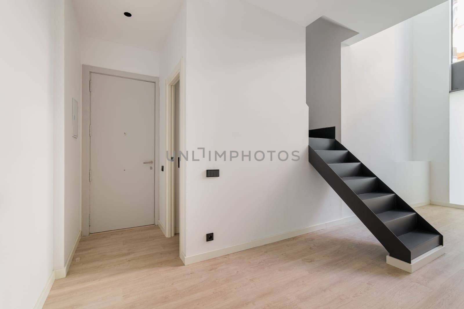 Interior of empty renovated apartment in a duplex flat with black stairs leading to the second floor