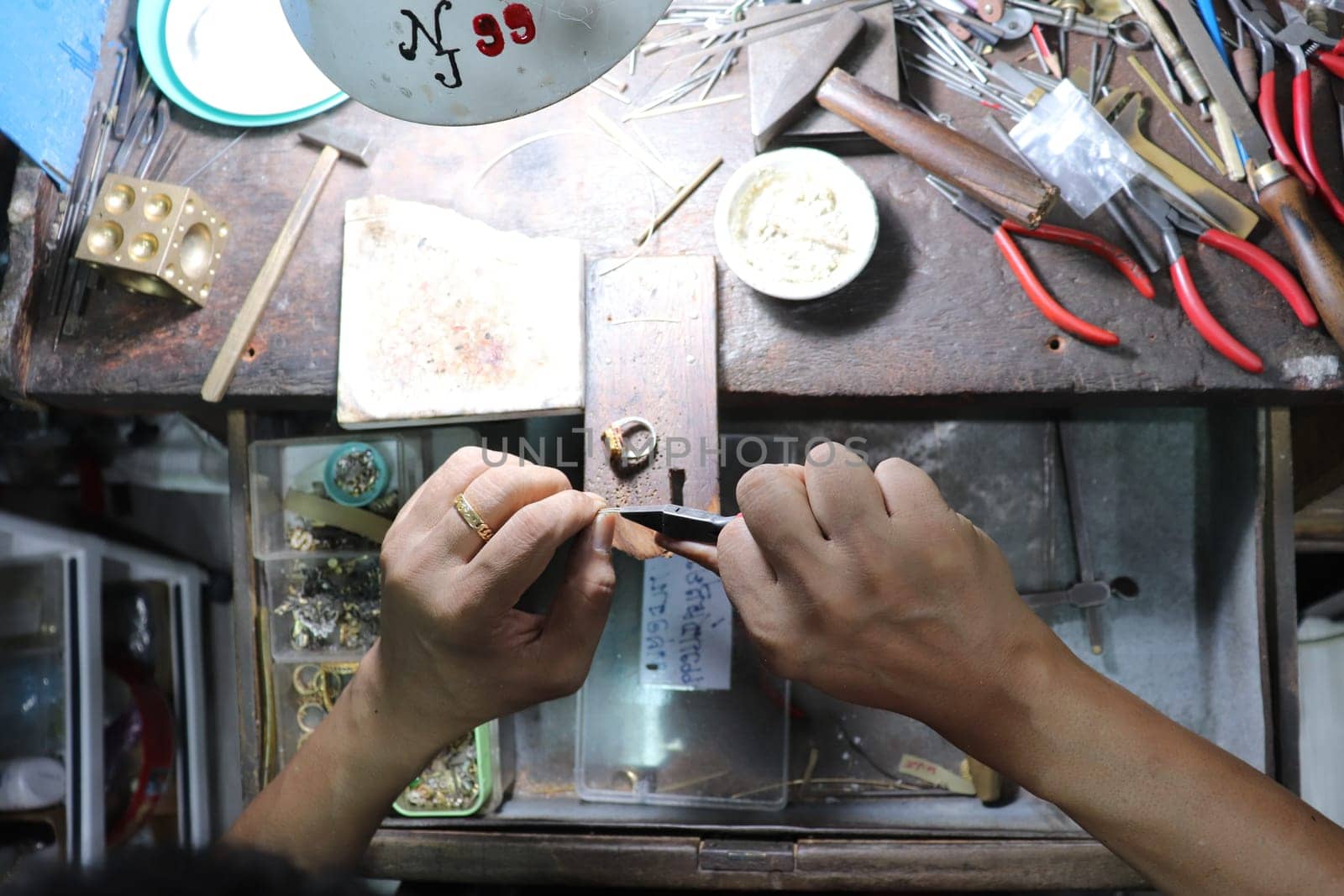 Old wood table for goldsmith with gold ring. Jeweler in Asia. Ancient and handmade jewelry work