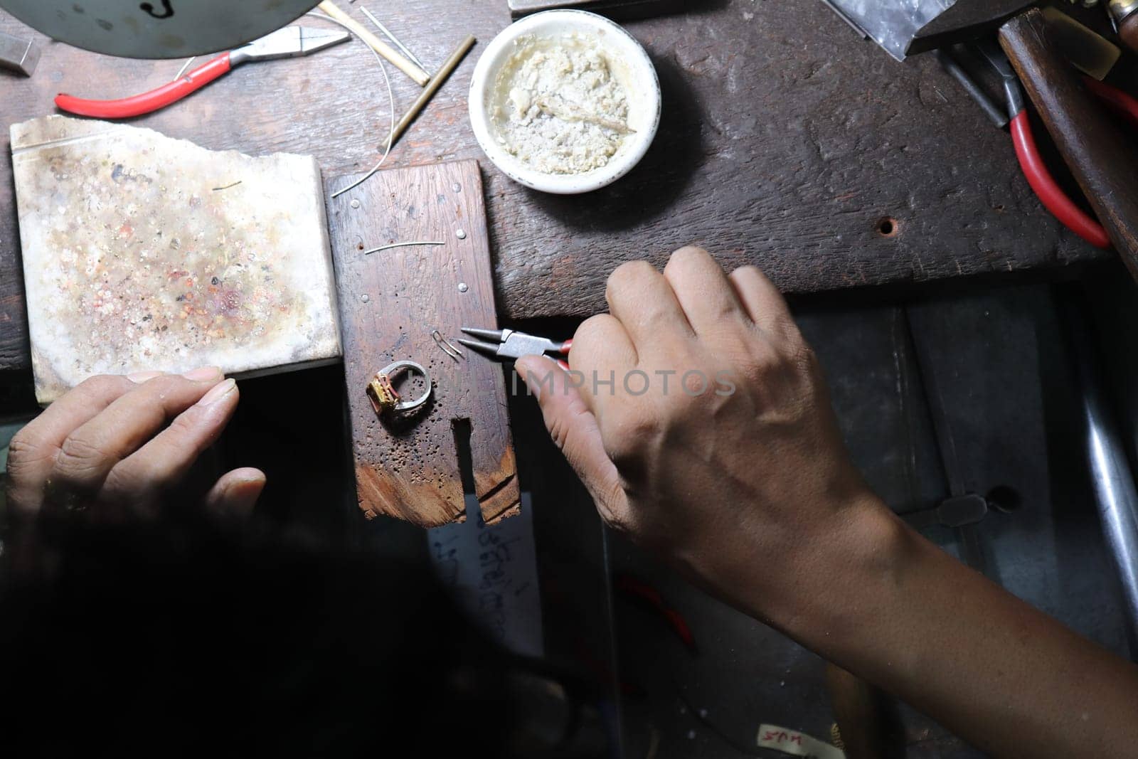 Old wood table for goldsmith with gold ring. Jeweler in Asia. Ancient and handmade jewelry work