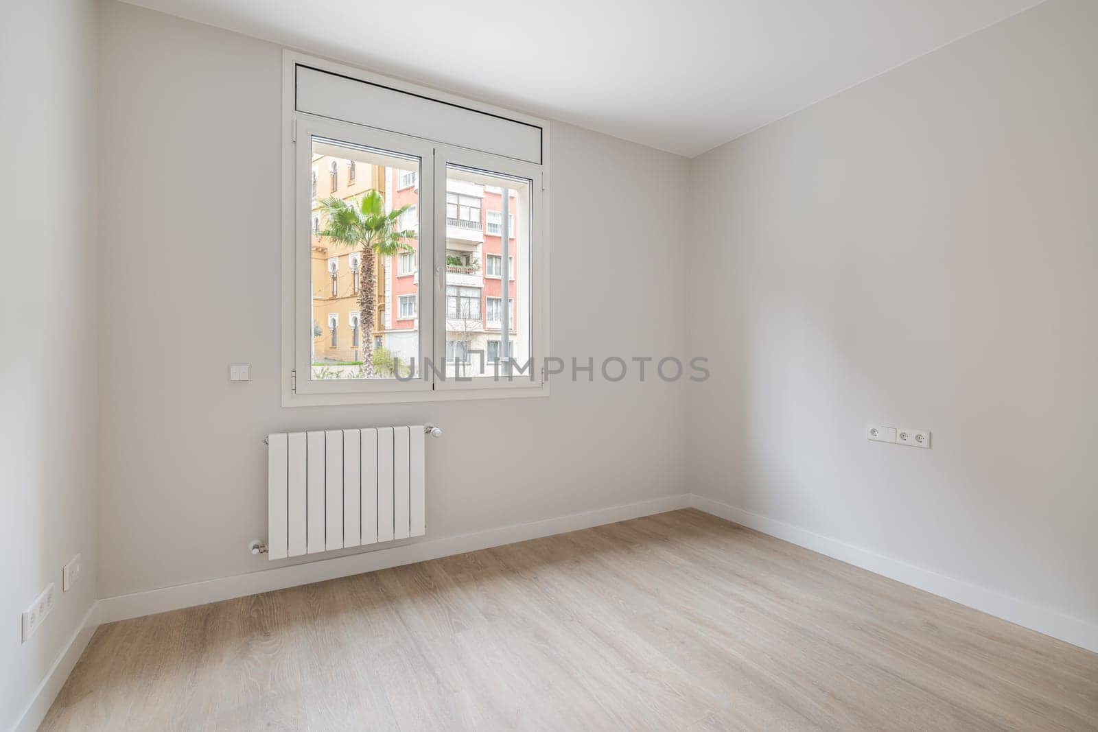 Empty white room with heating and window with city view. Interior of a modern apartment. by apavlin