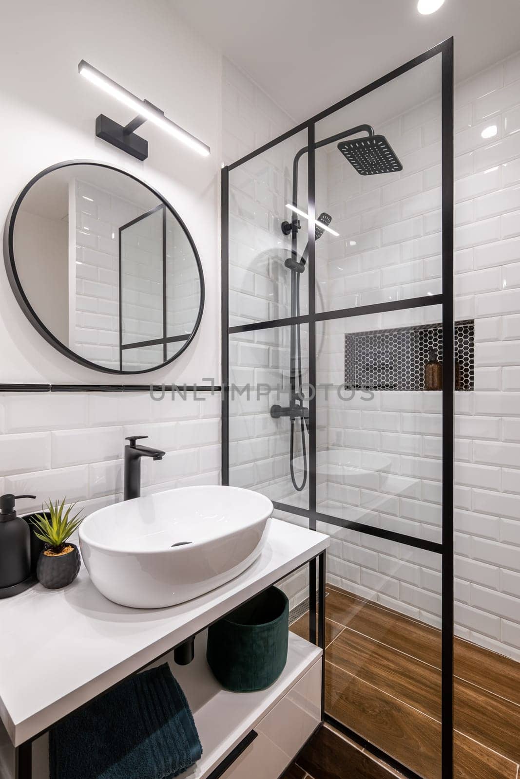 Simple bathroom with black shower, round mirror and classic white tiles.