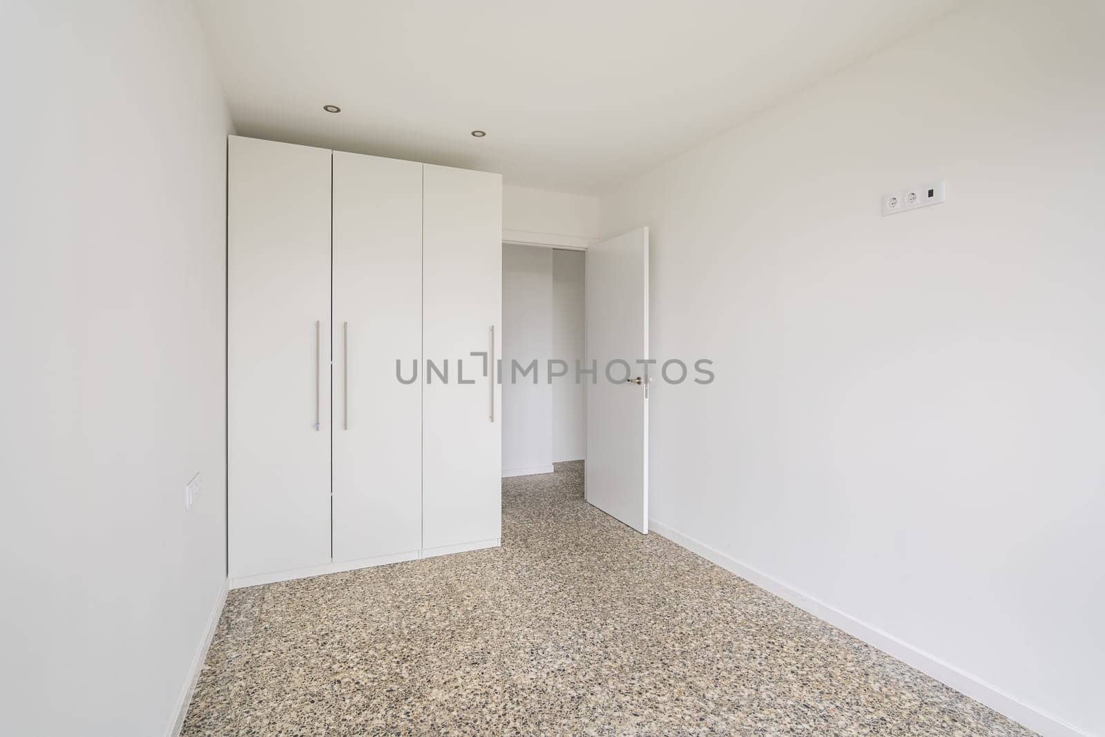 Interior of empty apartment, white room with wardrobe and tiled floor.