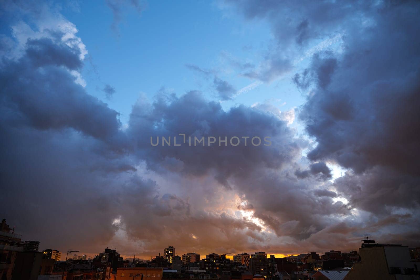 Blue sky at sunset twilight over city lights with heavy clouds.