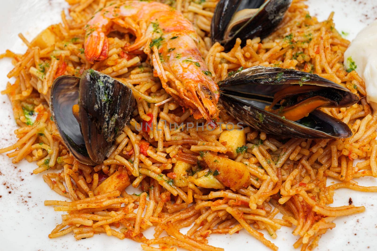 Noodles with tomato sauce and seafood, mussels and shrimps on white plate