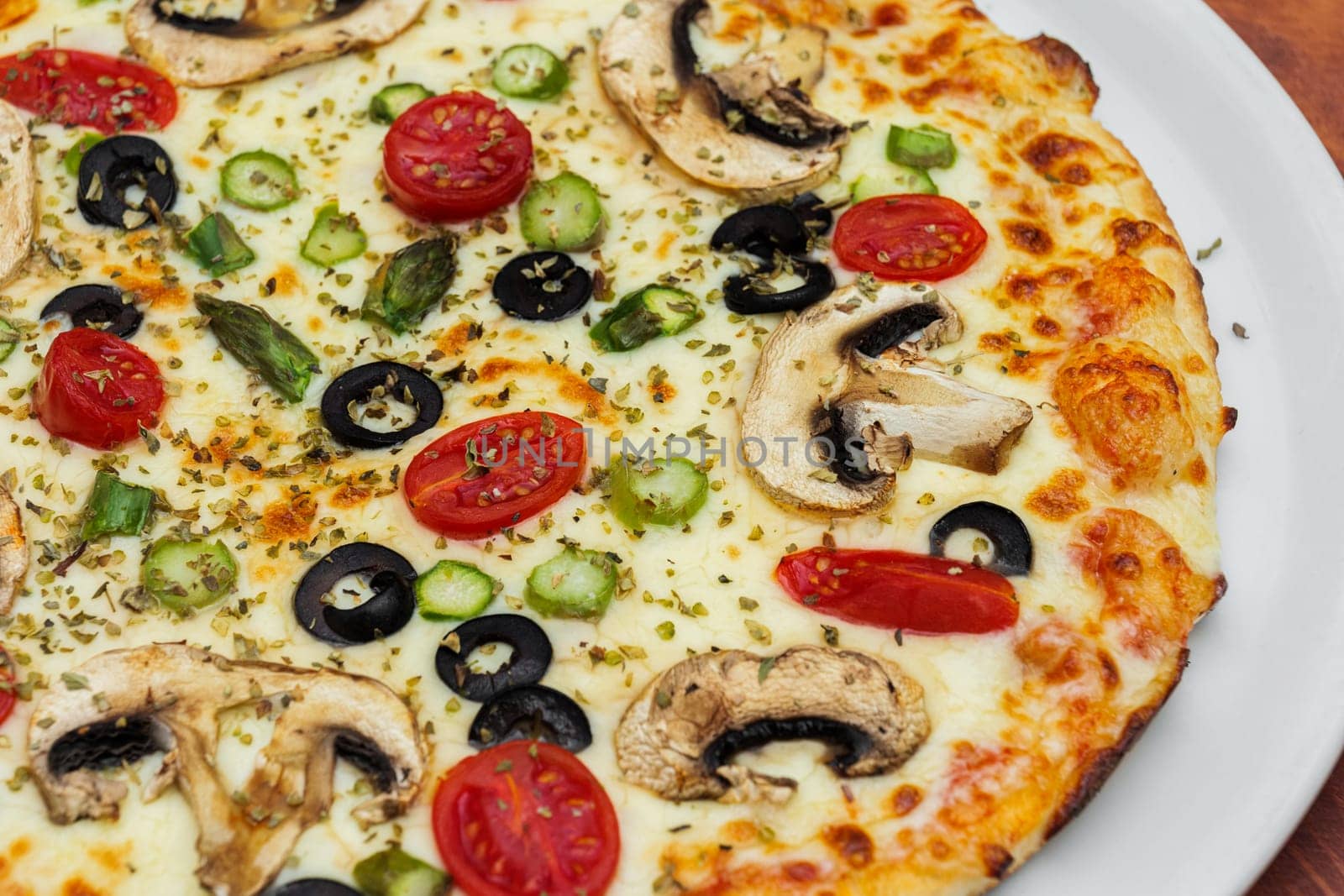 Vegetarian pizza on white plate. Mushrooms, cheese, black olives and tomatoes cherry