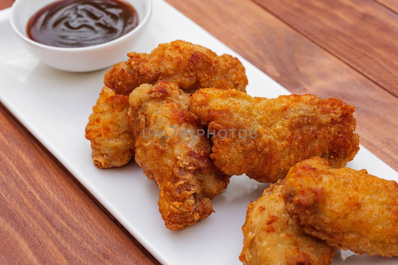 Fried chicken wings with barbeque sauce. Breaded Crispy fried chicken on wooden table. Deep fried food
