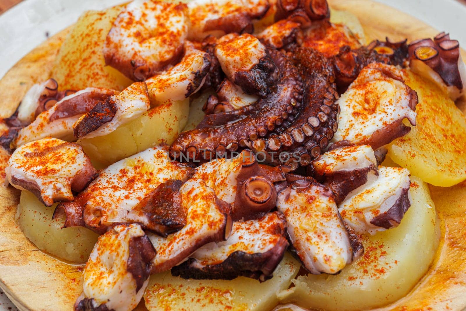 Fried octopus with potatoes and paprika on a plate in a restaurant.