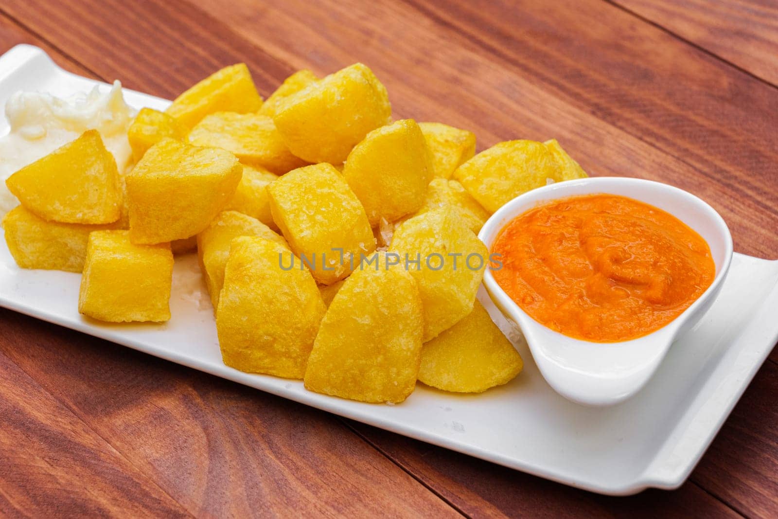 Fast food french fried potato with sauce on white plate and wooden background