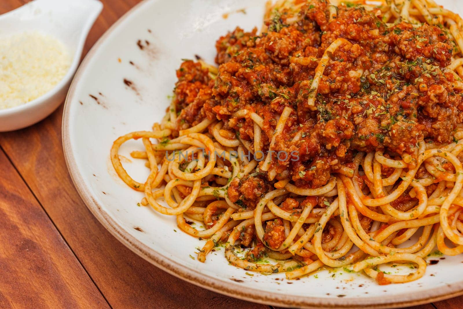 Spaghetti bolognese - pasta with minced meat and vegetables. Horizontal side view on wooden background.