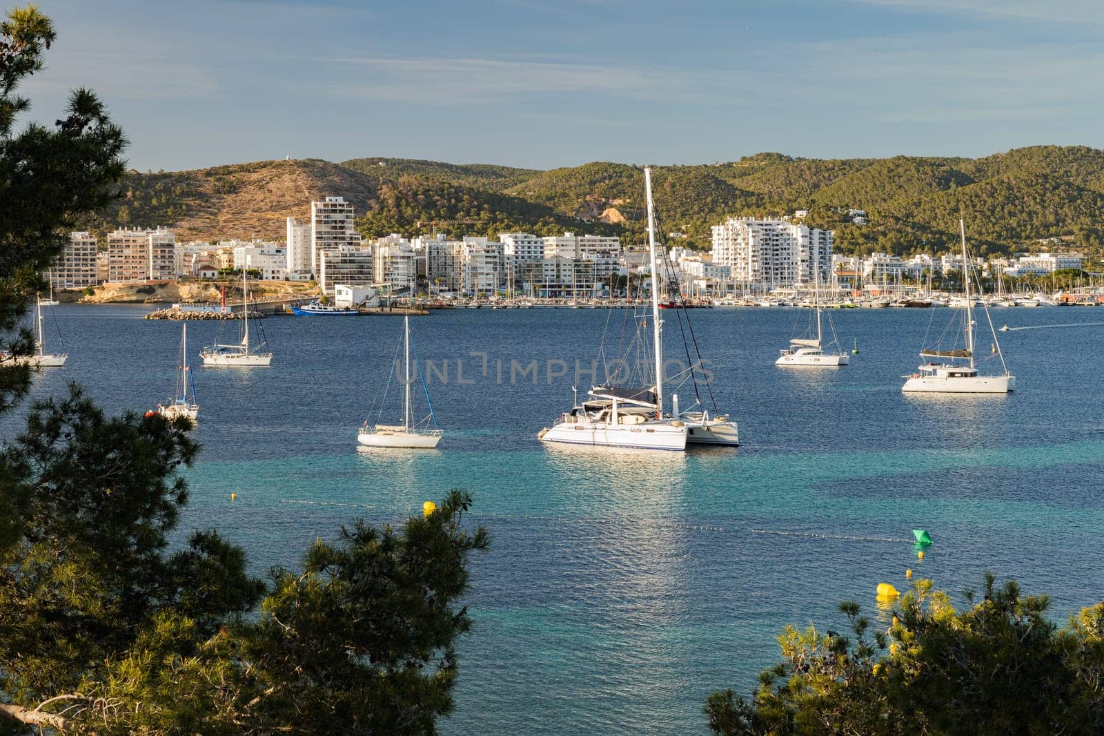 Bay of Ibiza coastline with turquoise water and yachts on sunny summer day