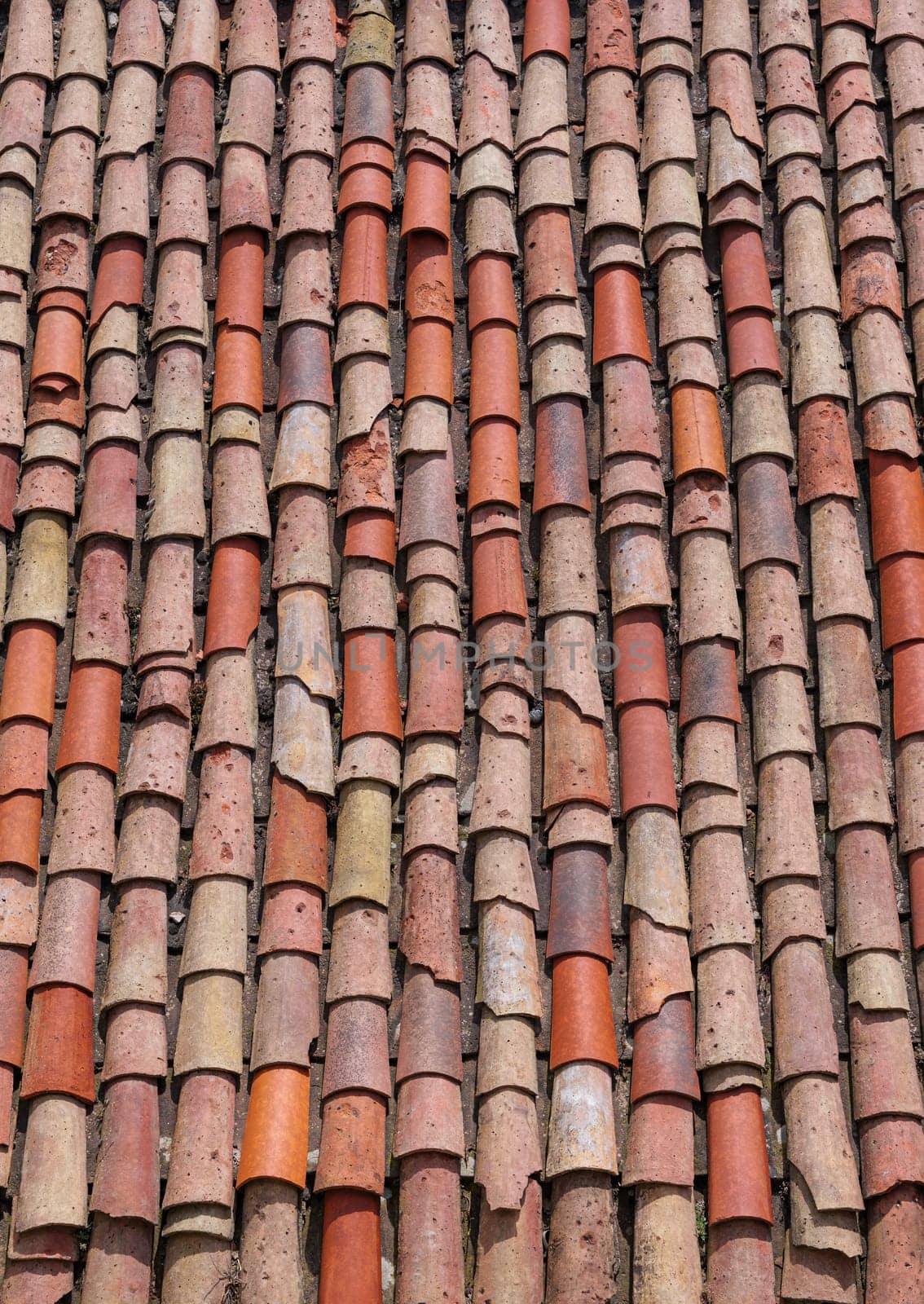 Vertical close-up of old weathered red and orange roof tiles. by apavlin