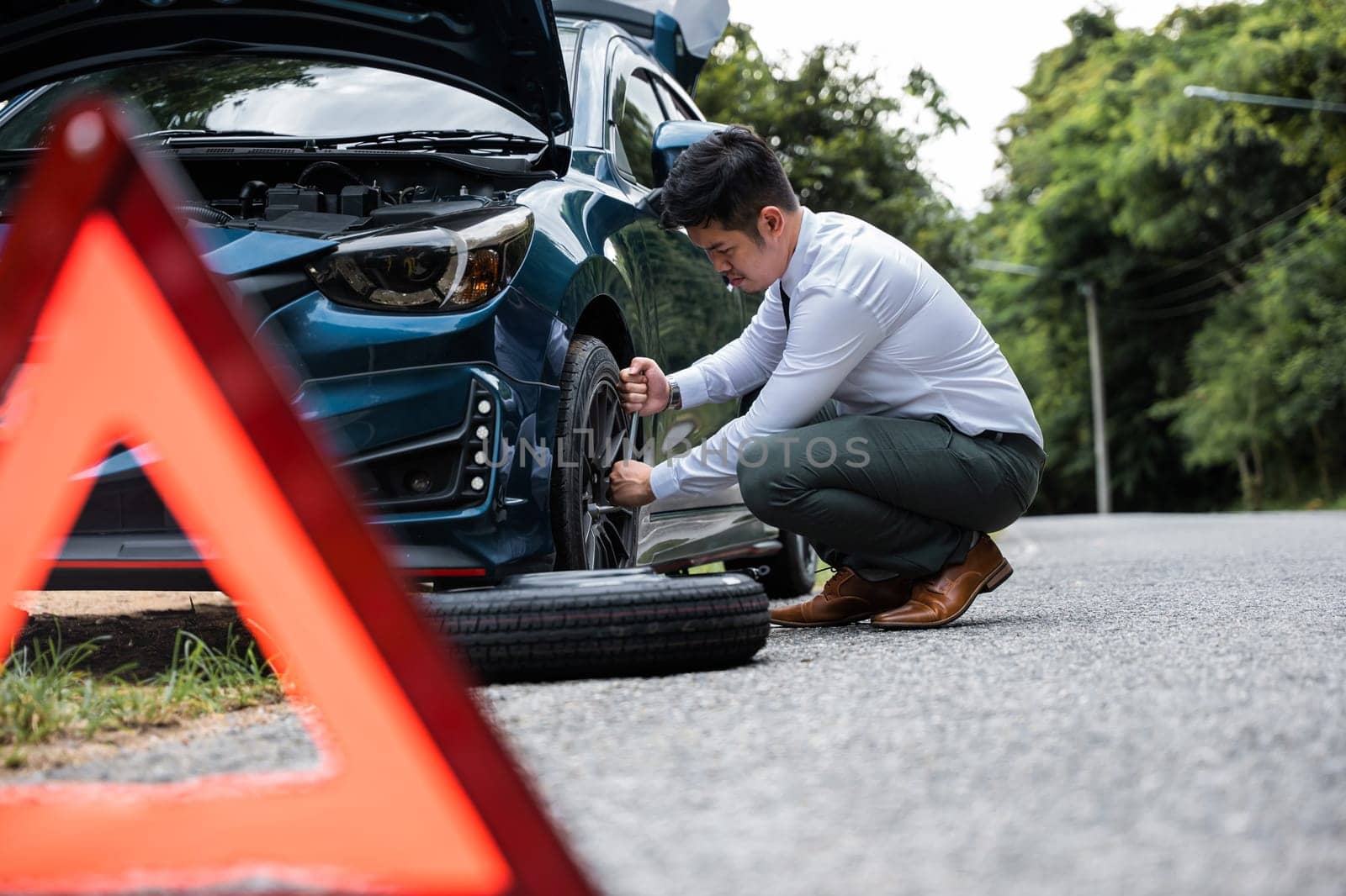 Asian businessman car broken has problems with wheel of his car by Sorapop