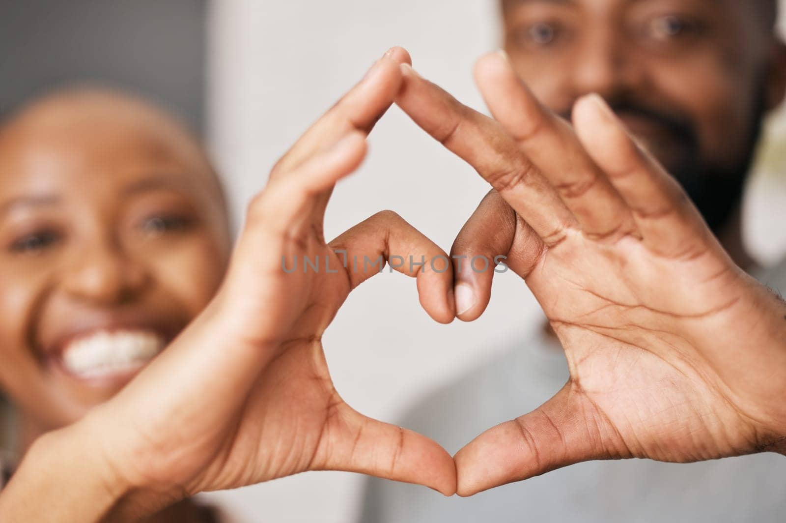 Happy, hands in heart and black couple with smile for relationship, dating and commitment in home. Love, emoji sign and face of black woman and man with hand shape for bonding, romance and trust.