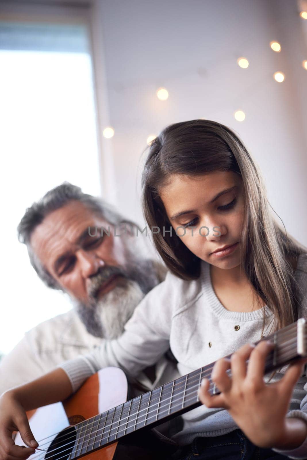 Girl with grandfather, guitar and learning to play, music education and help with creative development. Musician, art and old man helping female kid learn focus and skill on musical instrument.