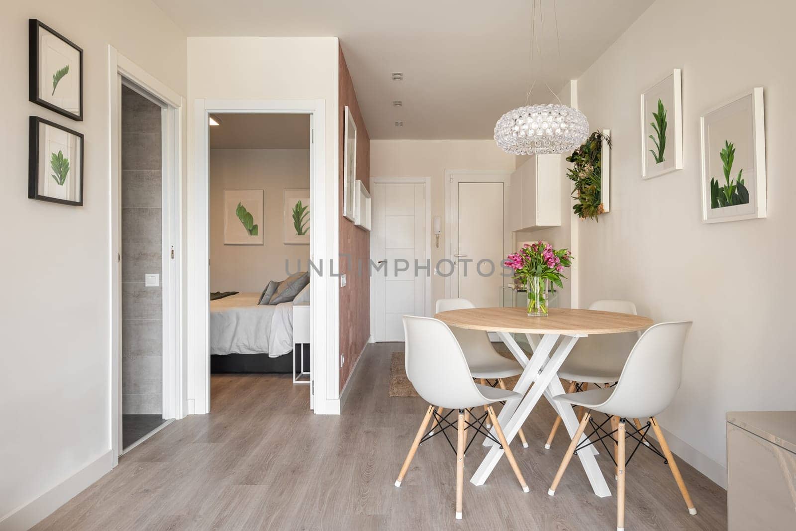 Stylish dining area in studio living room with table and chairs and decorative accessories overlooking the outdoor bathroom and bedroom. Concept of interior for a small apartment.
