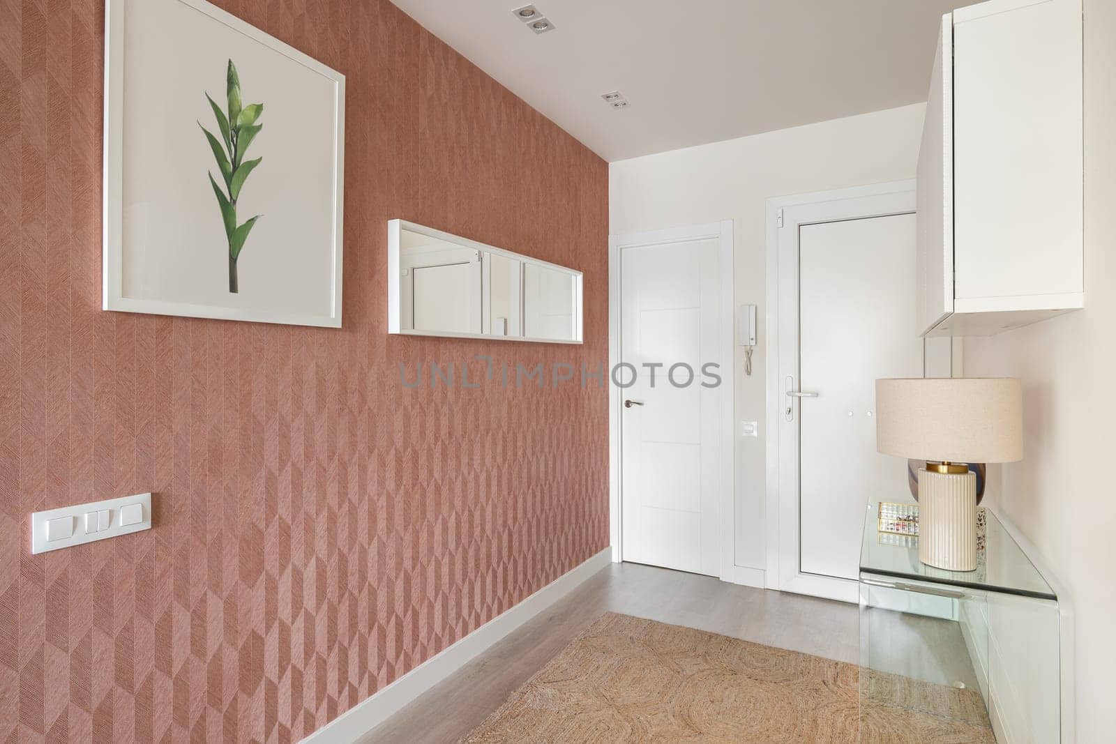 Modern stylish entrance hall with glass console and mirror and decorative accessories on pastel pink walls. The concept of a hotel for honeymooners in a hotel with a five-star service.