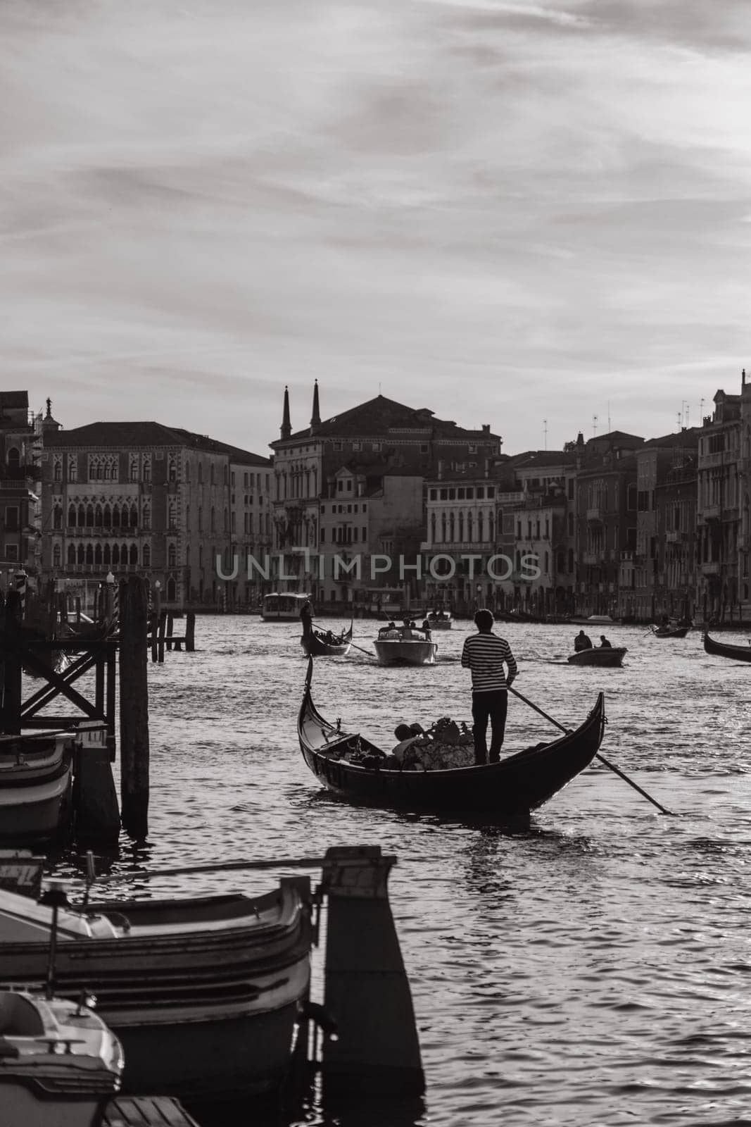 29 SEPTEMBER 2021, FLORENCIA, ITALY: Romantic black and white photo of tourists sitting in a gondola with a gondolier floating down a canal in Venice on warm summer evening