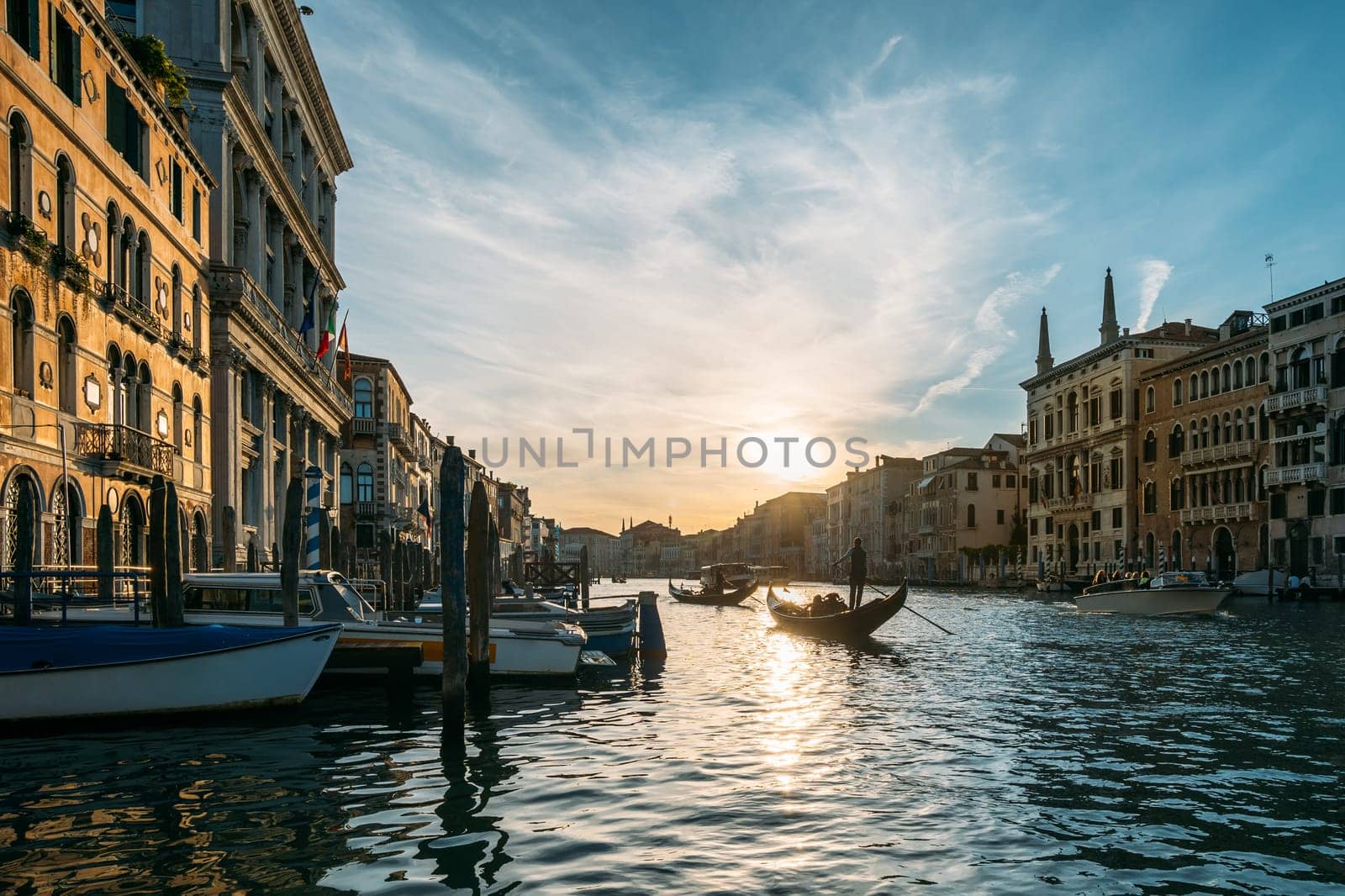 Gondolier on a gondola floats along a canal in Venice in the middle of ancient buildings on an early sunny morning. Beautiful romantic travel concept. Copyspac by apavlin