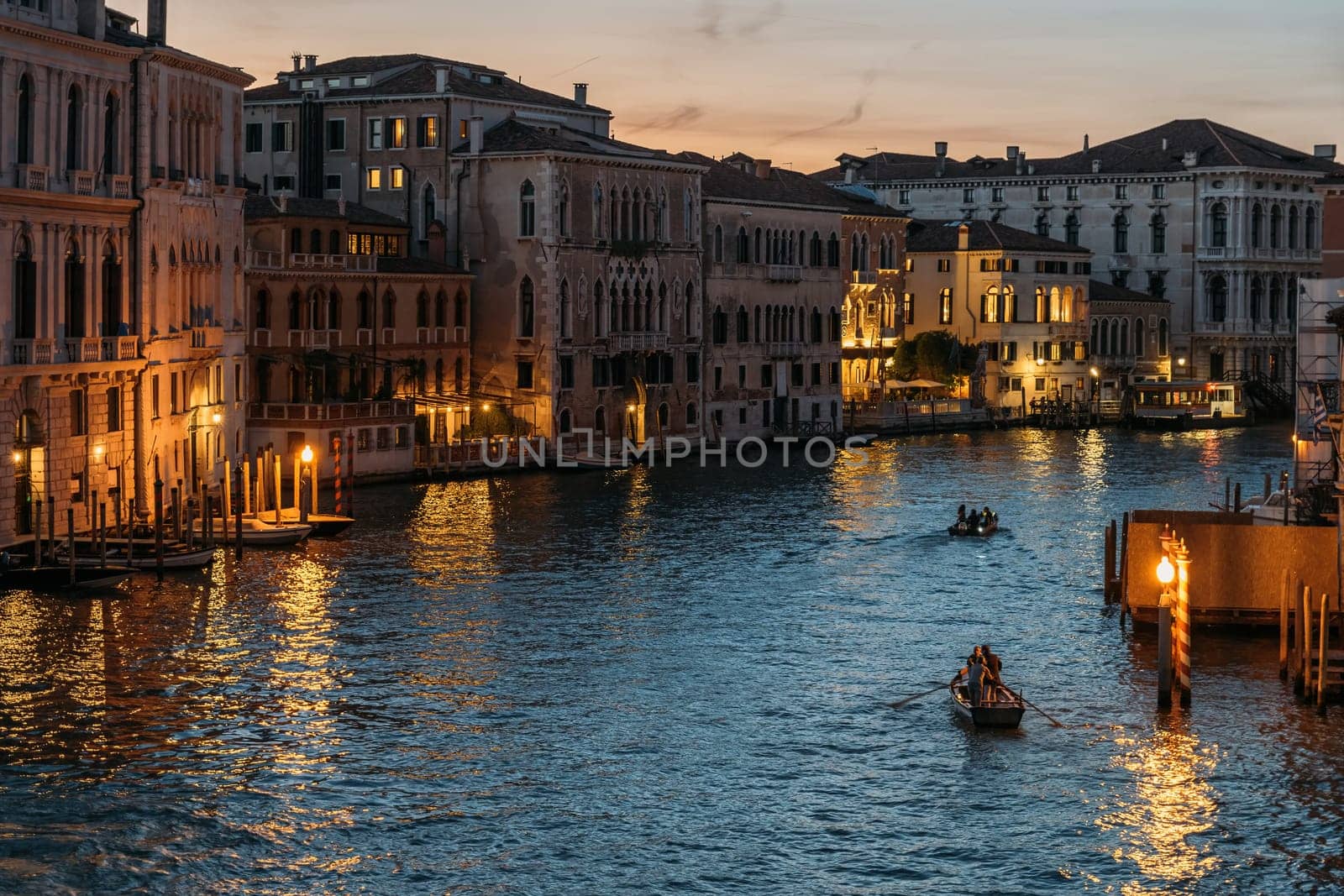 Top view of the beautiful Grand Canal in Venice with glowing lights on the blue sky on a summer evening. Tourist travel concept in the romantic city of Italy. Copyspace.