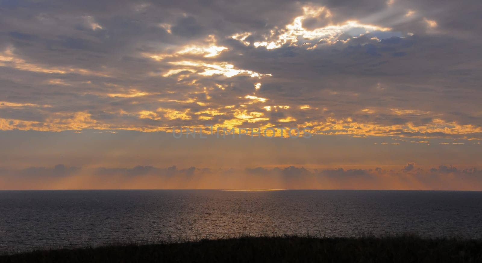 Colorful orange sunrise over the sea, sunbeams in the clouds