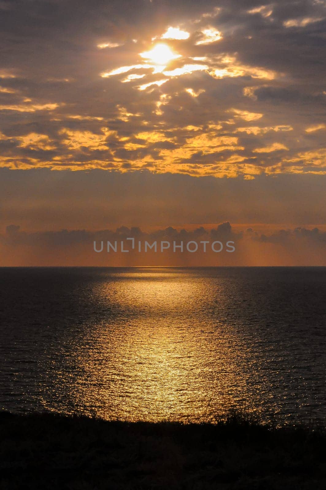 Colorful orange sunrise over the sea, sunbeams in the clouds